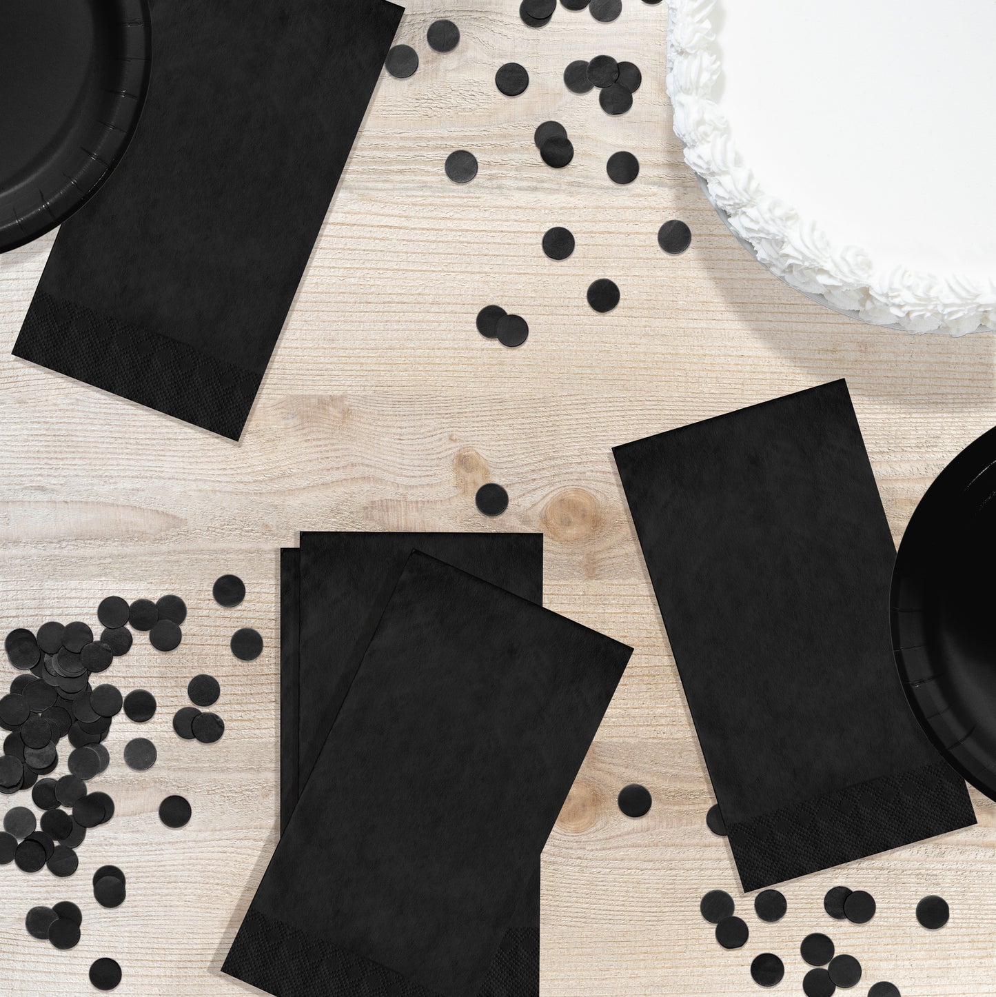 Black pin embossed guest napkins on a wood table with circle confetti