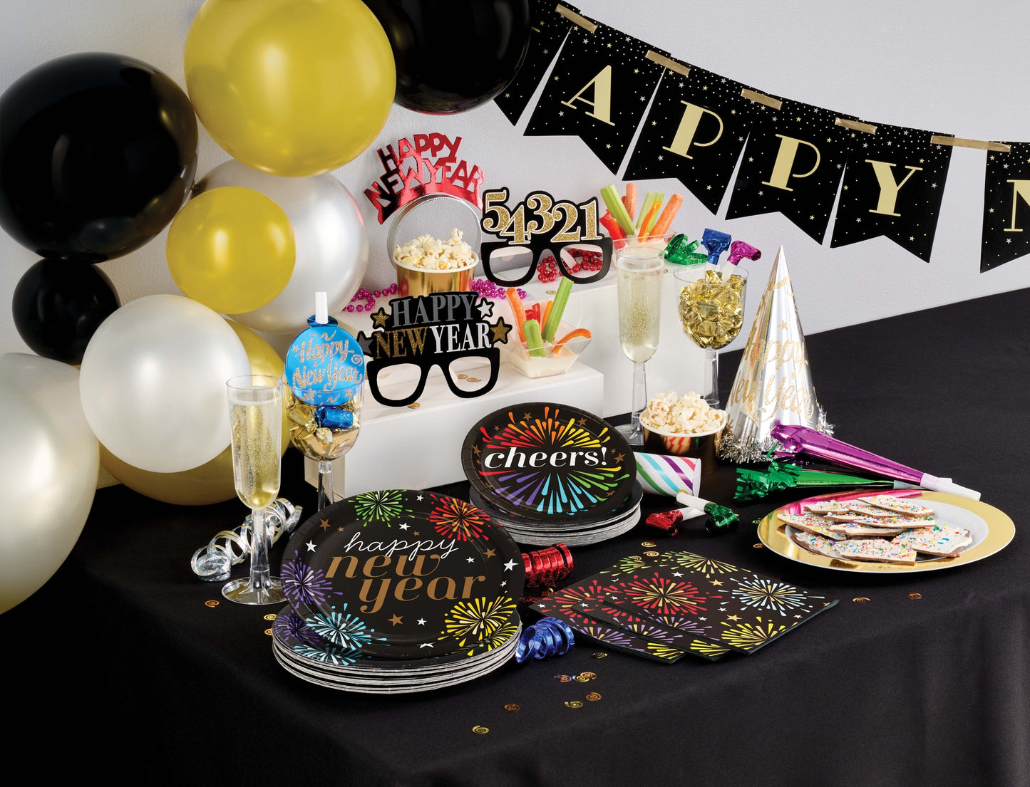 New Year's Eve party setup with balloons, cake, and decorations on a table.