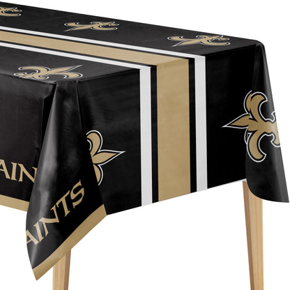 A black New Orleans Saints themed tablecloth draped over a table, featuring the team's gold fleur-de-lis logo, gold 'SAINTS' text, and vertical gold, white, and black stripes.