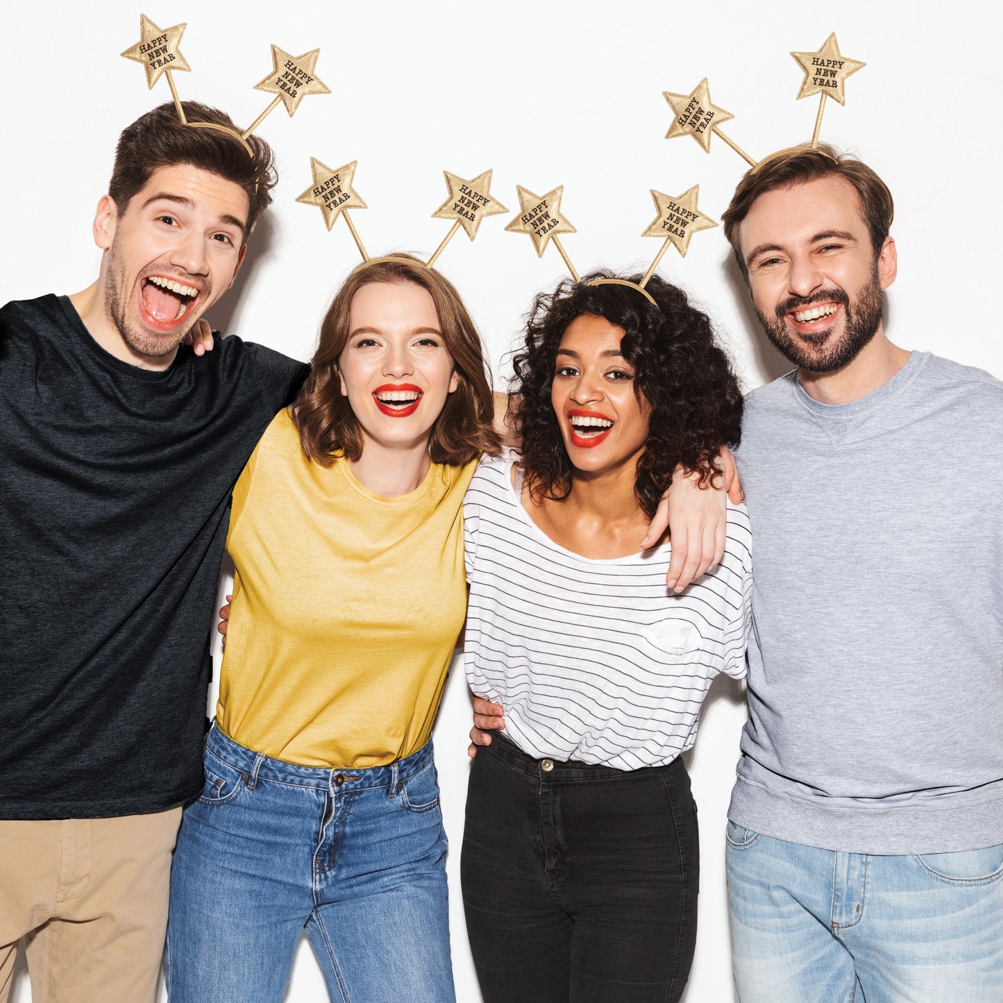 Four people posing together with star-shaped headbands that feature 'Happy New Year' on 2 stars.