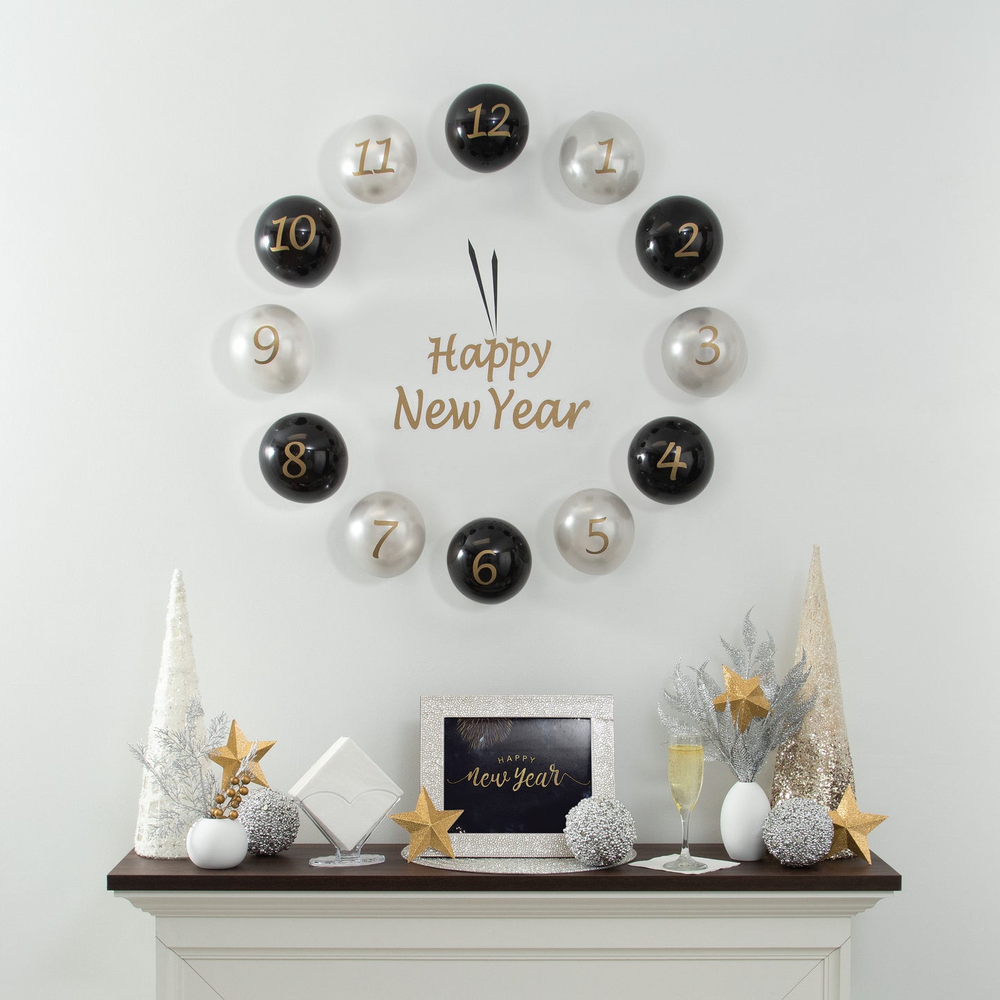 Decorative countdown clock with numbered black and silver balloons spelling 'Happy New Year' on a white wall above a fireplace