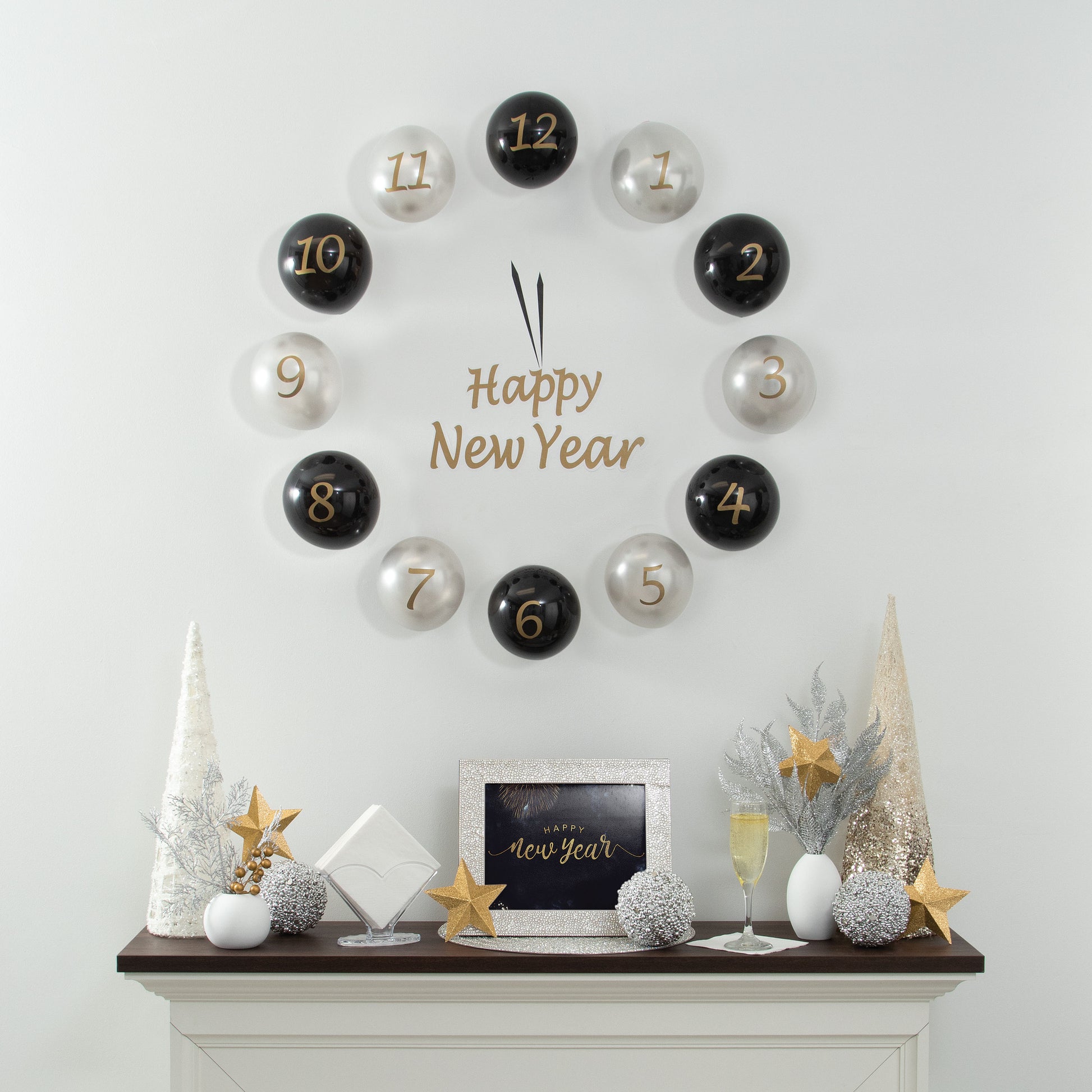 Decorative countdown clock with numbered black and silver balloons spelling 'Happy New Year' on a white wall above a fireplace