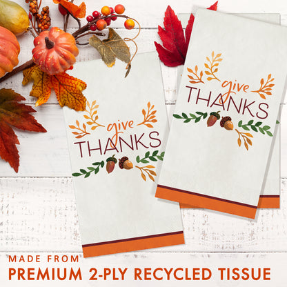Fall Festivities Give Thanks Thanksgiving Dinner Napkins 192 ct. Two 'give THANKS' paper napkins with autumn decorations on a white wooden surface with autumn decorations.