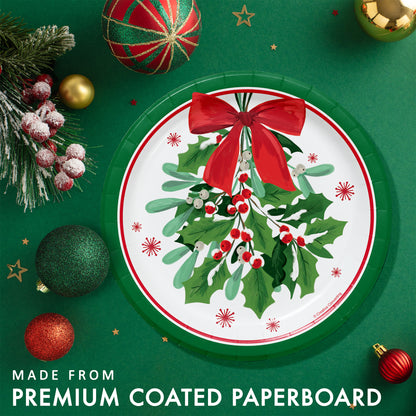 Decorative paper plate with holly design and green rim. Featured on a green background with Christmas ornaments and greenery.