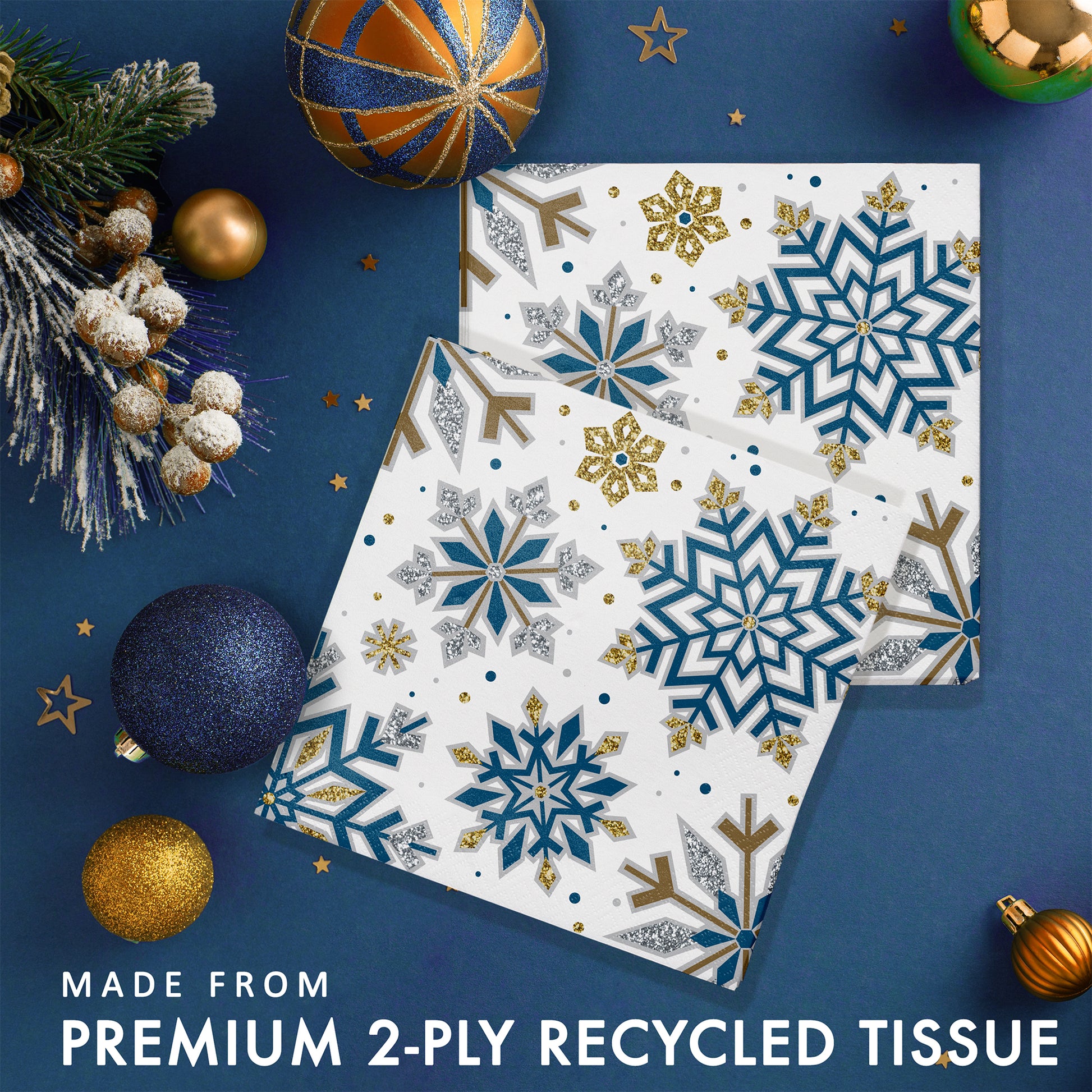 Blue, gold and silver nowflake-patterned paper napkins. Shown on a blue background with decorative Christmas balls and ornaments.