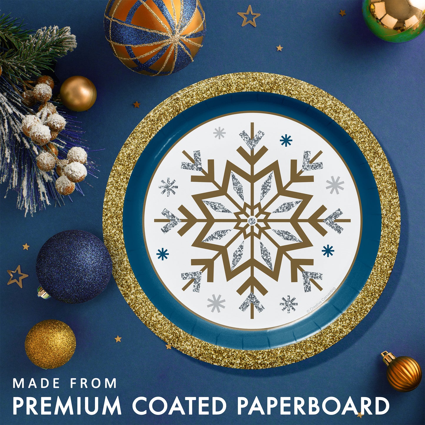 Decorative paper plate with gold and silver snowflake design with a blue and gold rim. Plate shown on a blue background with Christmas ornaments.