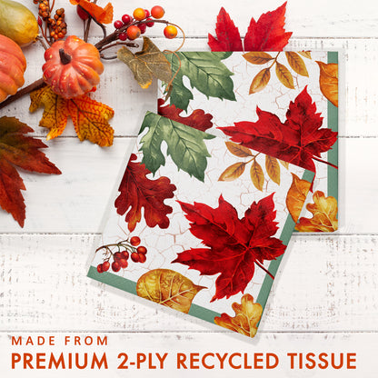 Autumn Air Luncheon Napkins 192 ct. Napkin with autumn leaf design on a white wooden surface with pumpkins and berries.