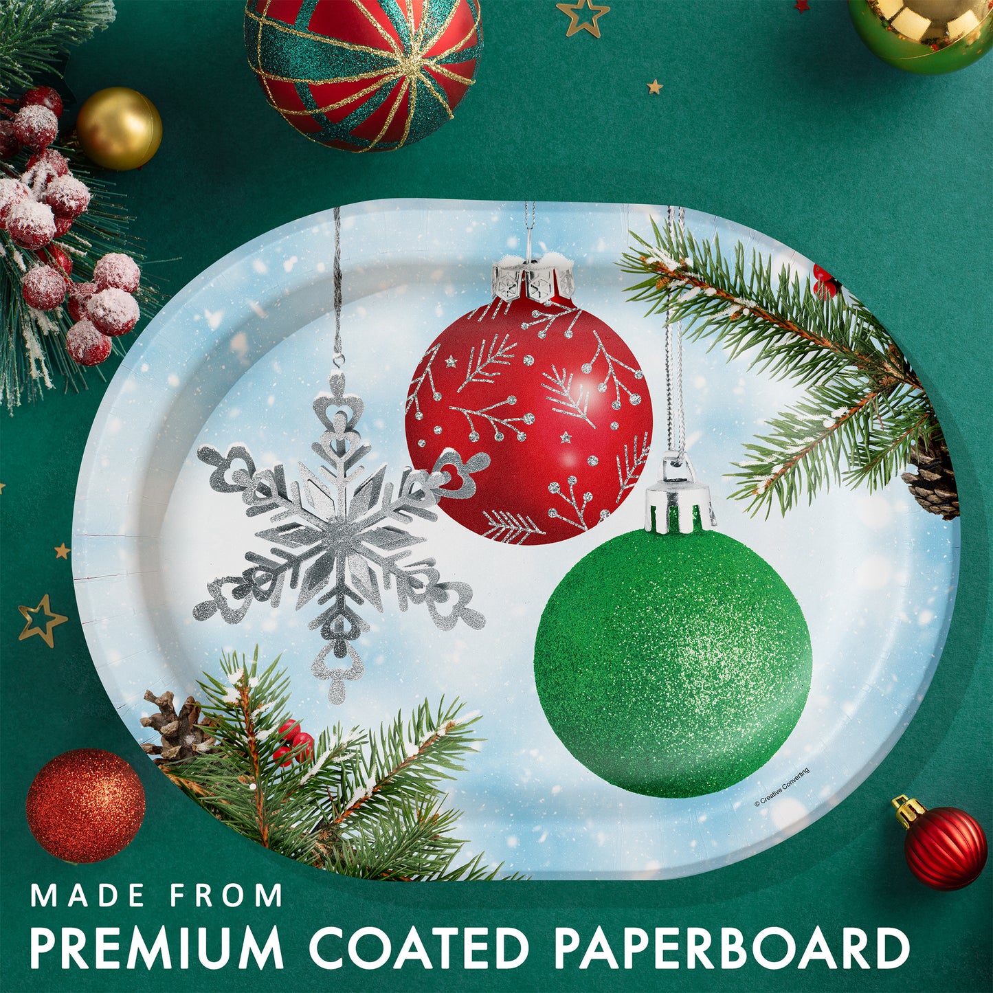 Decorative paper plate with Christmas ornaments on a green background with holiday decorations and greenery