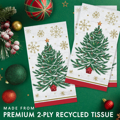 Two Christmas-themed paper napkins with tree designs and gold snowflakes. Napkins shown on a green background with festive decorations.