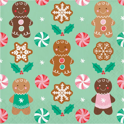 Christmas-themed paper napkin with gingerbread men, snowflakes, holly, and peppermints on a green background.