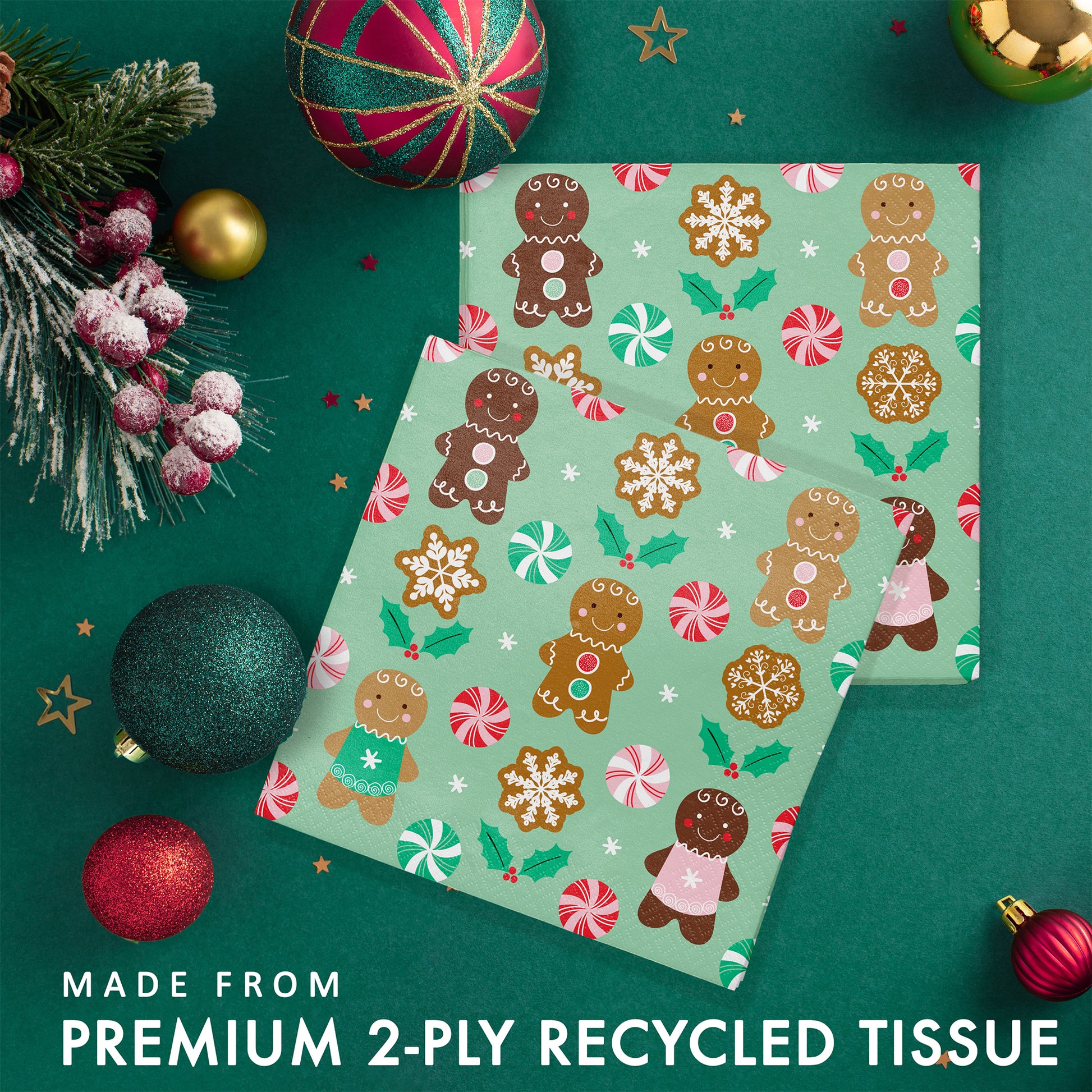 Two sets of green paper napkins with gingerbread man pattern. Napkins shown on a green background with Christmas decorations and greenery.