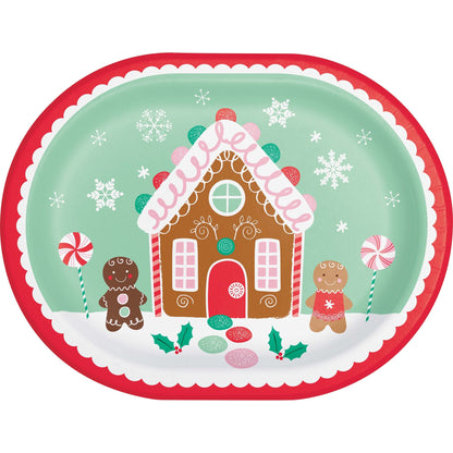 Oval decorative paper plate with a gingerbread house design and gingerbread men on a white background