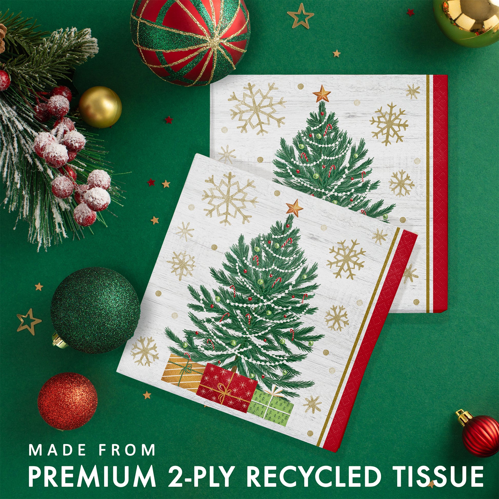Christmas-themed paper napkins with trees and presents. Napkins shown on a green background with festive decorations.