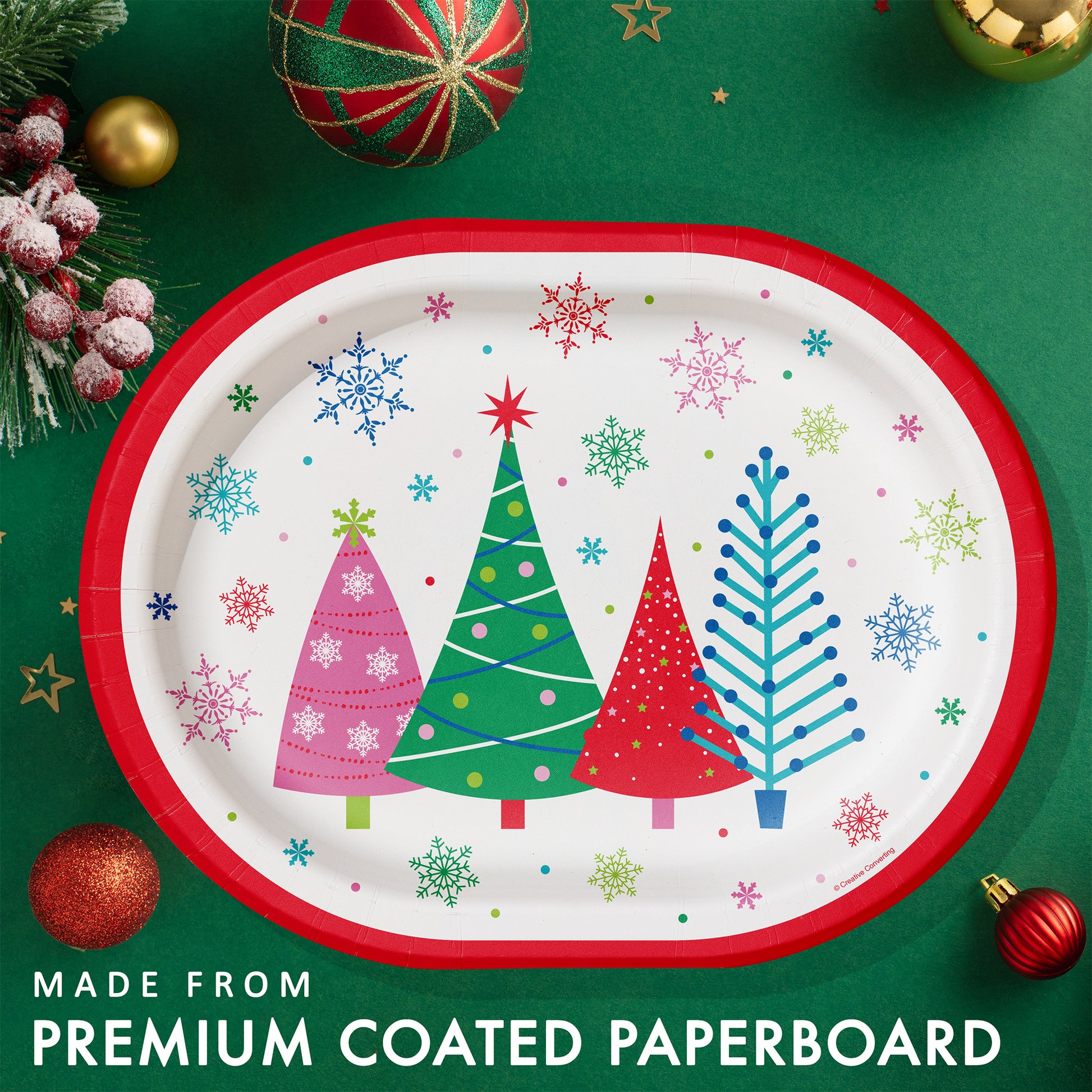 Joyful and Jolly Oval Dinner Paper Plates 96 ct. Christmas-themed paper plate with trees and snowflakes on a green background with festive decorations.