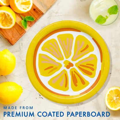 Paper plate with lemon design surrounded by lemons and a glass with mint leaves on a light background