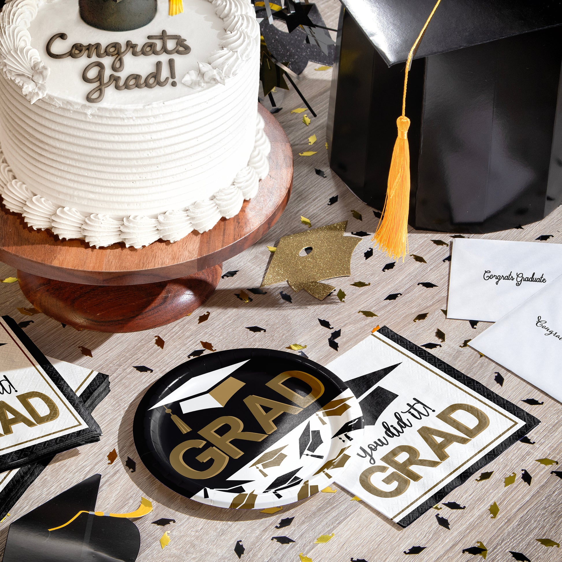 Graduation-themed table setting with cake, decorations, plates, napkins, and graduation decorations