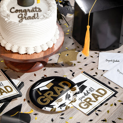 Graduation-themed table setting with cake, decorations, plates, napkins, and graduation decorations