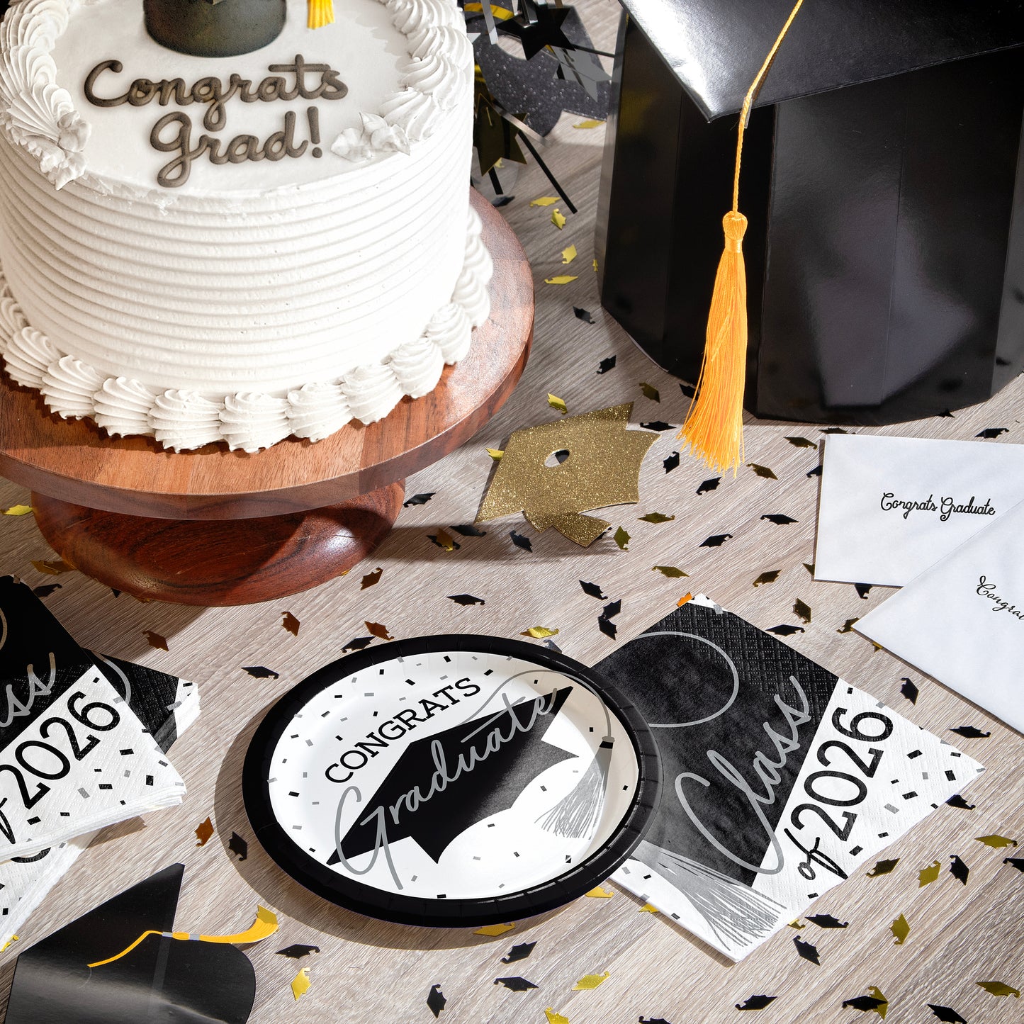 Graduation-themed table setting with cake, decorations, napkins, plates and graduation decorations.