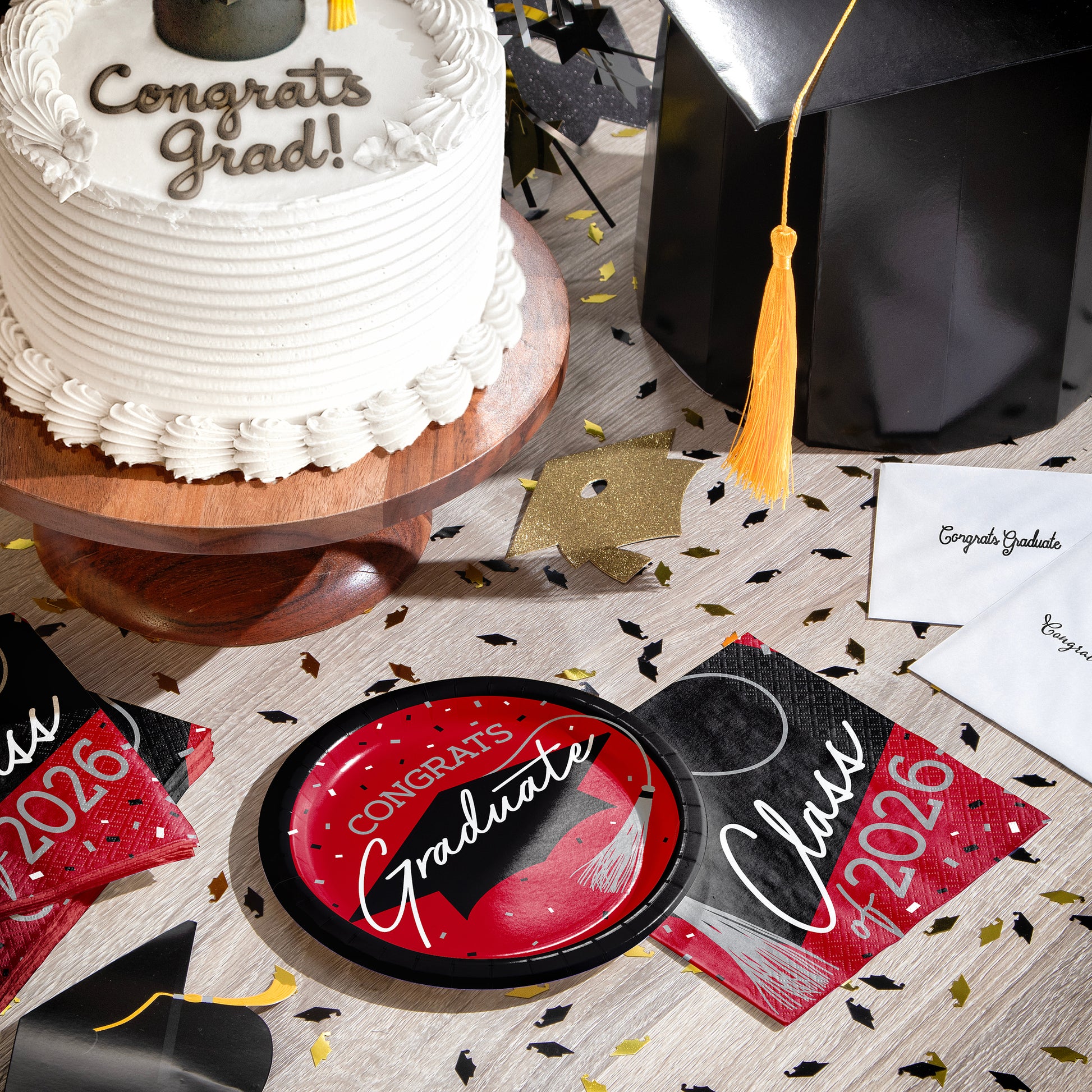 Graduation-themed items including a cake, plates, napkins and a graduation cap on a table.