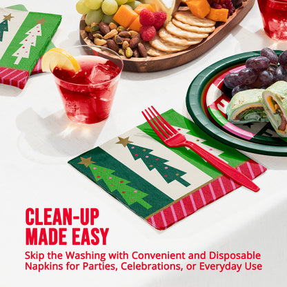 Christmas-themed disposable paper napkins with green tree patterns and red striped borders, shown on a white tablecloth with a red drink, plates, grapes, and a charcuterie board. Text at the bottom reads 'CLEAN-UP MADE EASY'.