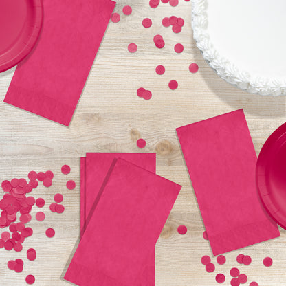 Pink paper plates and napkins with confetti on a wooden surface
