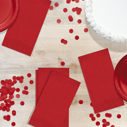 Red pin embossed guest napkins on a wood table with red circle confetti