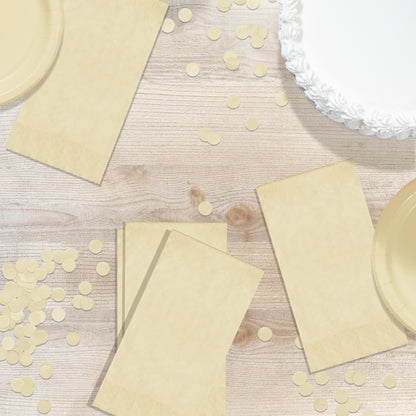 Ivory pin embossed dinner napkins on a wood table with confetti and a white cake