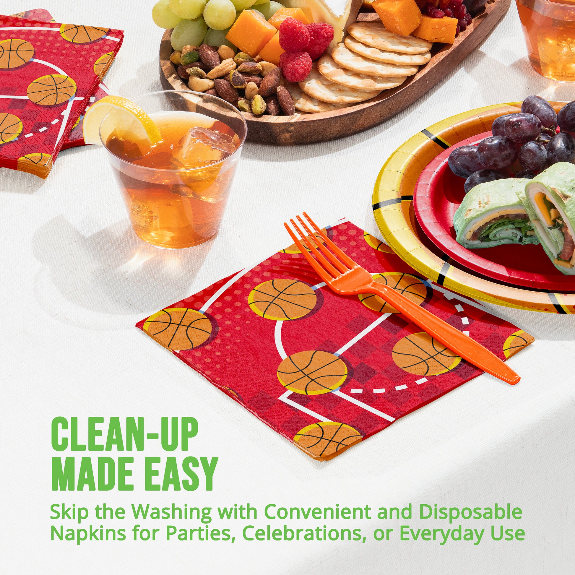 Disposable party supplies including plates, napkins, and cutlery with food on a table.
