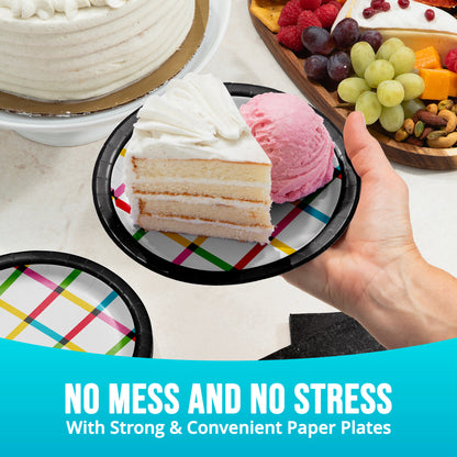 Hand holding a paper plate with cake and ice cream, surrounded by more plates and desserts.