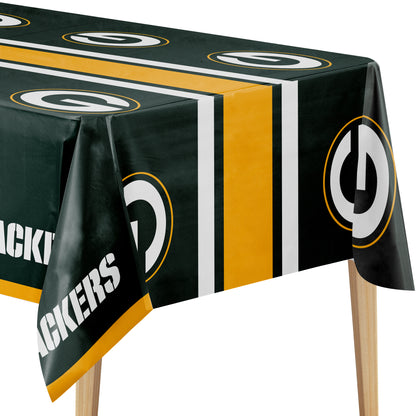 Close-up image of Green Bay Packers tablecloth with green background, "G" logo, and "PACKERS" text on a wooden table