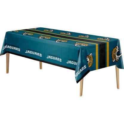 A rectangular table covered with a teal Jacksonville Jaguars themed tablecloth, shown on a plain white background. The tablecloth features the team name, jaguar logos, and a black and gold center stripe, with the wooden table legs visible underneath.