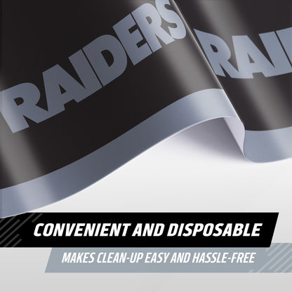 A close-up of a Raiders tablecloth with bold silver lettering with 'RAIDERS' on a black background, shown with text overlays reading 'CONVENIENT AND DISPOSABLE' and 'MAKES CLEAN-UP EASY AND HASSLE-FREE'.