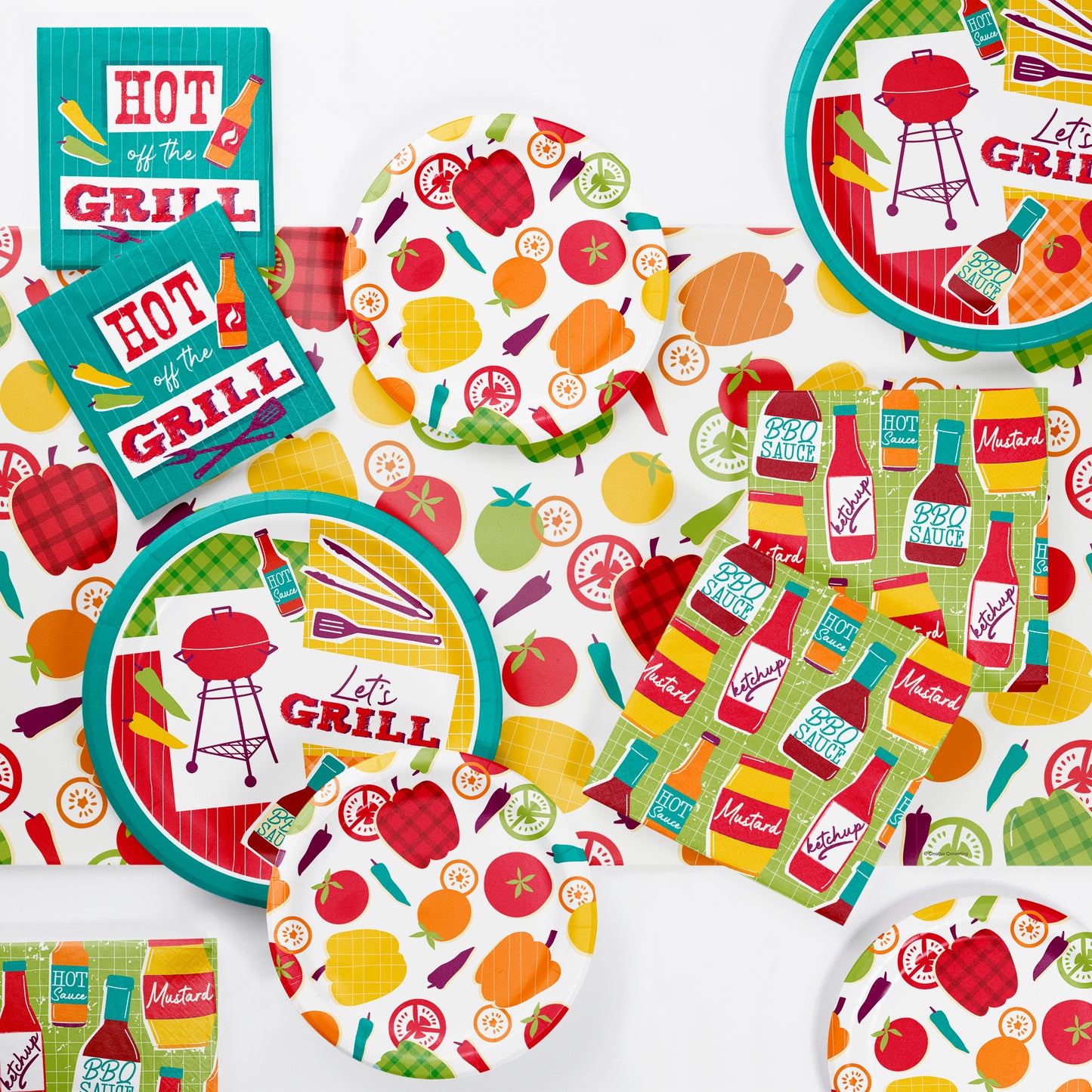 Colorful barbecue-themed tableware set with plates and napkins on a matching barbecue-themed tablecloth