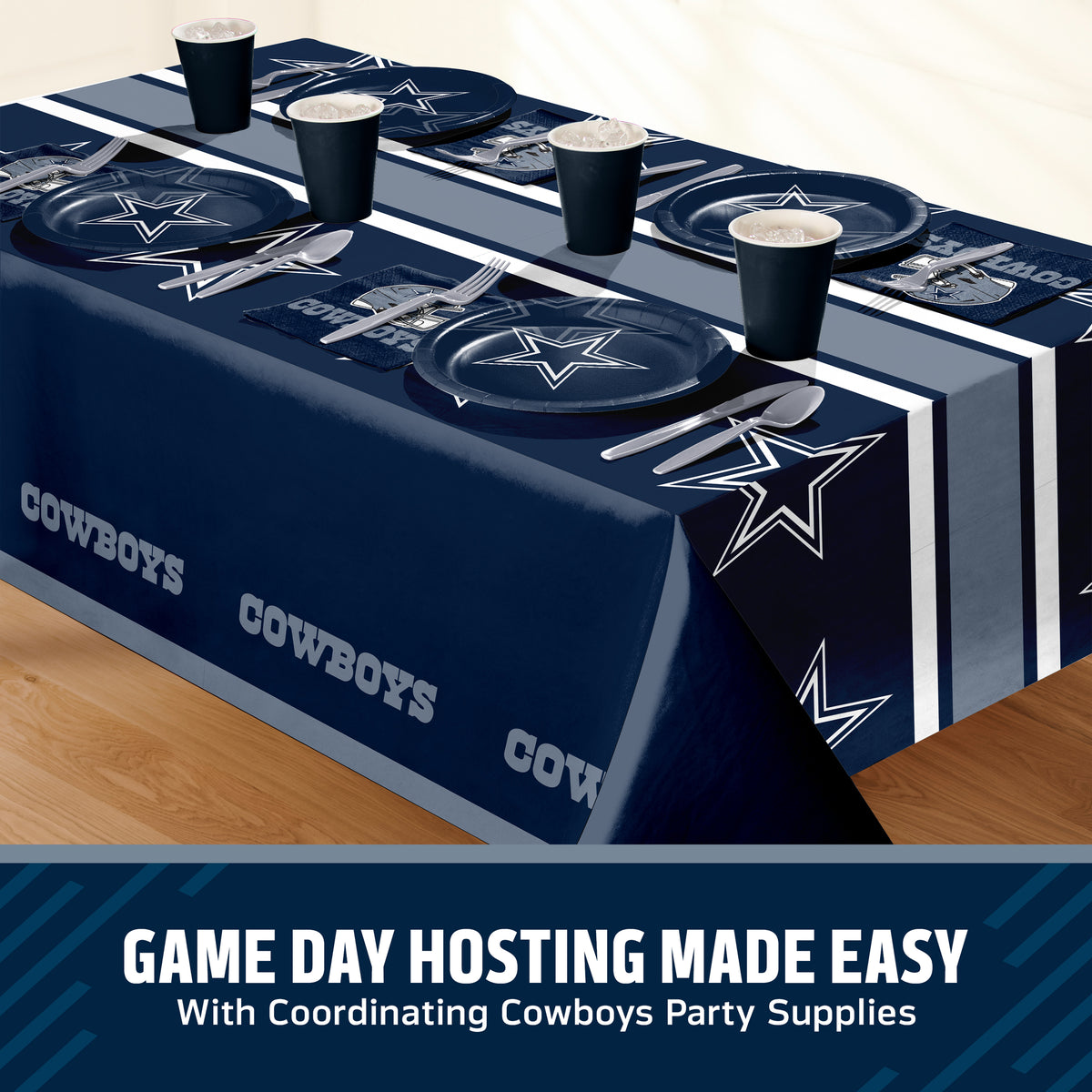 A Dallas Cowboys themed party table setting featuring a navy blue tablecloth with white star and logo prints, matching navy plates, navy cups, and silver cutlery, displayed on a wooden table with a promotional text banner at the bottom.