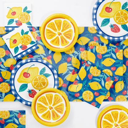 Colorful tableware set including napkins and plates with lemon, strawberry, and cherry design on a matching tablecloth.