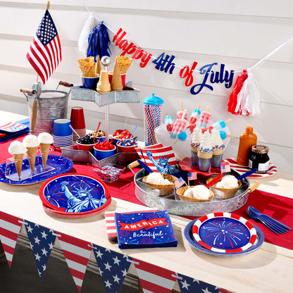 Table setting for 4th of July celebration with decorations, food, and a 'Happy 4th of July' banner.