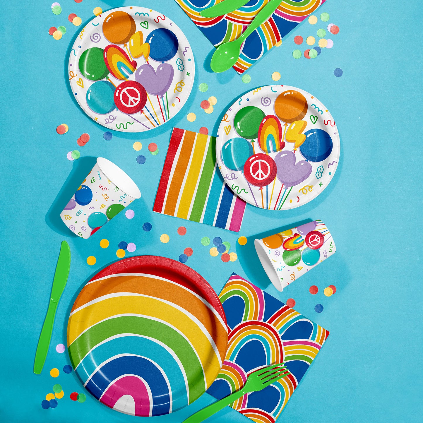 Colorful partyware set with plates, cups, napkins, and utensils on a blue background