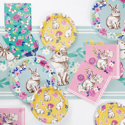 Easter-themed party supplies including plates, napkins, and tableware with bunny and floral designs on a light blue background.