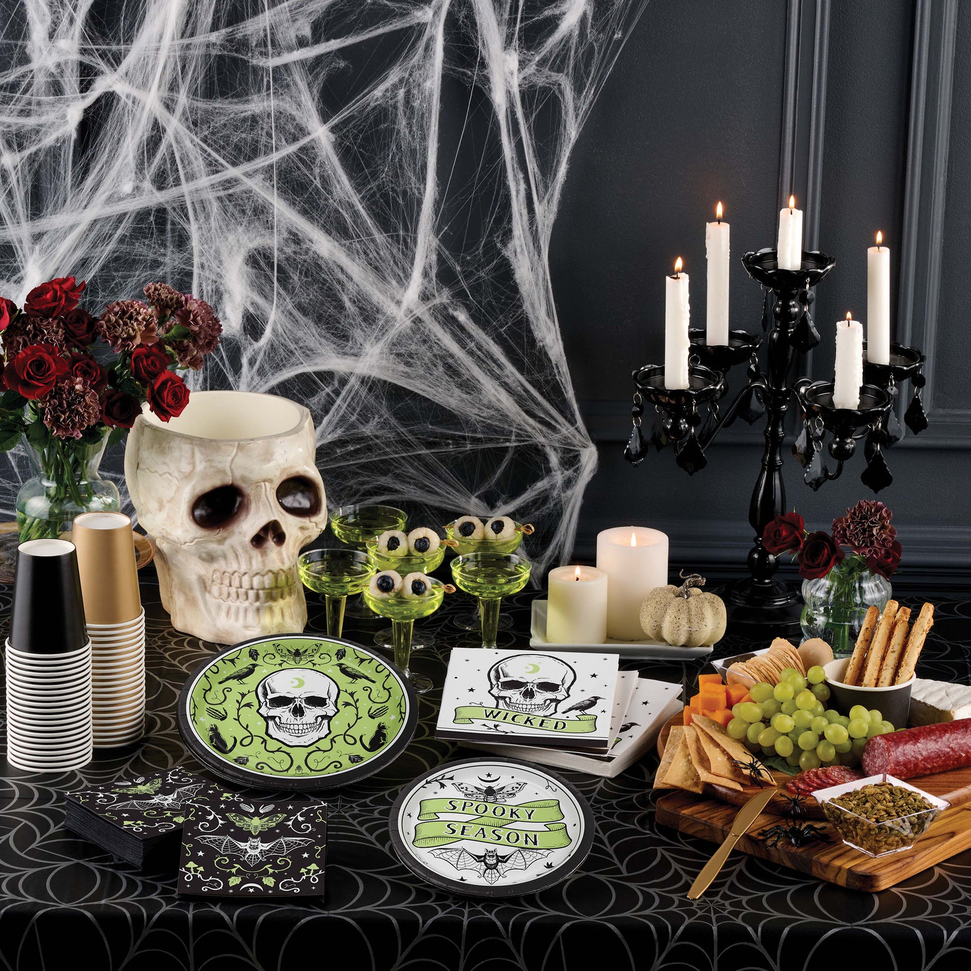 Halloween-themed table setting with skull decorations, candles, and spider webs.