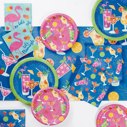 Colorful party supplies with flamingo and cocktail designs on a matching blue tablecloth
