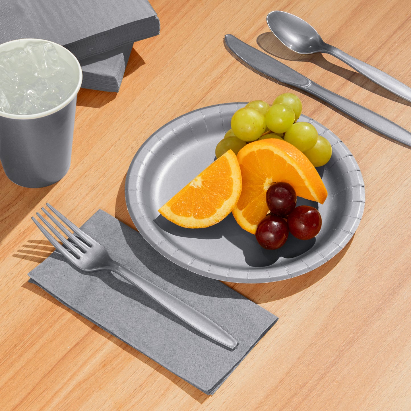 Silver plate with fruit, silverware, and a cup on a wooden table