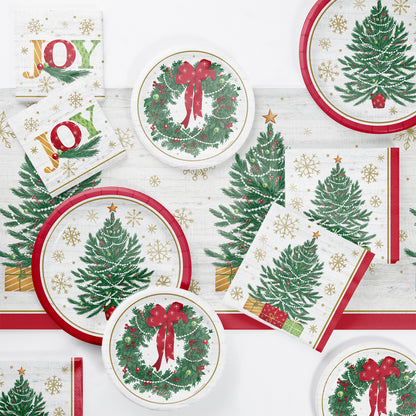 Christmas-themed paper plates and napkins with trees, wreaths, and 'JOY' text on a white background.